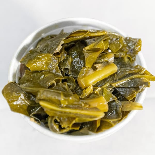 Close-up overhead view of a bowl filled with glistening, dark green collard greens.