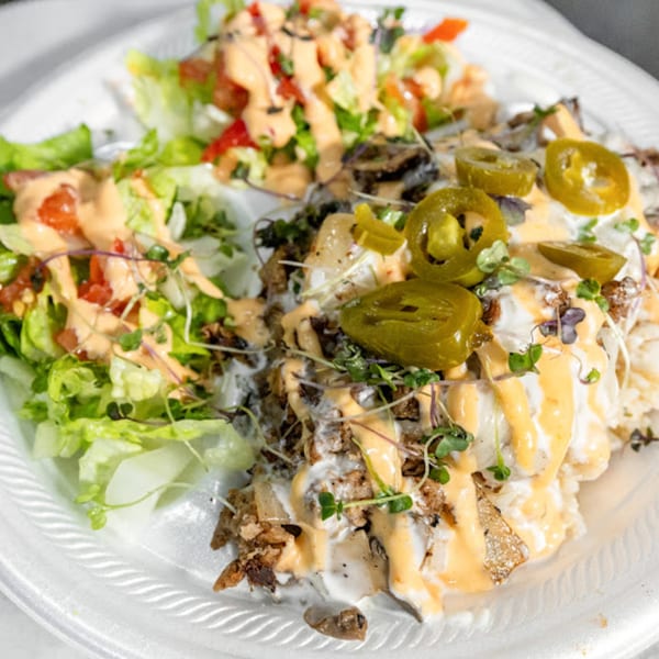 Plant Bae's vegan dish with rice, plant-based meat, jalapenos, and a side salad with dressing.
